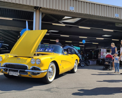 Eine gelbe Corvette Jahrgang 1962 steht mit offener Motorenhaube vor einer Halle.