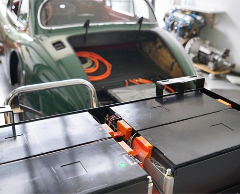 Im Vordergrund die hintere Batteriebox mit Batteriemodulen befüllt. Im Hintergrund das Heck des Jaguars XK150.