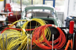 Gelbe und rote Kabel, zusammengerollt, die aus der Batteriebox herausschauen. Im Hintergrund das Fahrzeug, in welches die Batteriebox eingebaut wird.