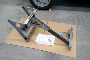 Ein Metallgestell, an welchem Motor und Batterie im Fahrzeug befestigt werden. Es liegt noch ausserhalb des Fahrzeugs, auf einem Karton. Ebenso auf dem Bild ein Ausdruck des CAD-Modells der Halterung mit Motor