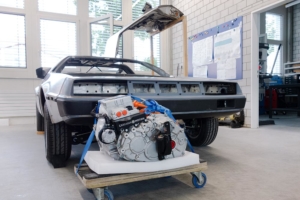 Der Elektromotor plus Umrichter und Getriebe/Differenzial auf einem Rollbrett vor dem Fahrzeug.