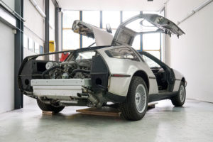 Heckansicht eines DeLorean DMC-12, leicht schräg. Die Stossstange fehlt, ebenso die Heckklappe. Daher sieht man einen Teil des Rahmens sowie den Motor.