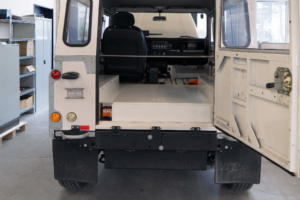 Das Heck eines Land Rover Defenders, mit Sicht auf die Ladefläche. Die Batteriekiste in Wagenfarbe findet auf der Ladefläche platz.