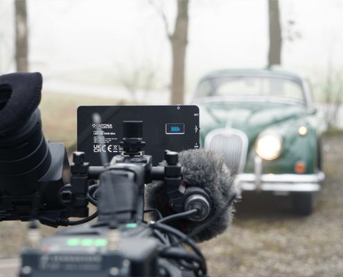 Eine Kamera von hinten aufgenommen, wie sie auf den Jaguar XK 150 ausgerichtet ist. Im Hintergrund neblige Landschaft