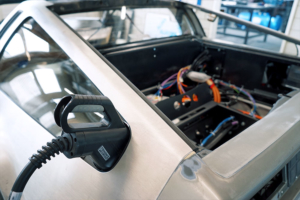 Heck des DeLoreans, ein CCS-Stecker ist am hinteren Ende des hinteren Seitenfensters eingesteckt. Er passt gerade knapp in die Lücke, die sich in dem Bereich ergibt.