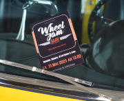 Ein Flyer für das Young- und Oldtimer-Treffen "Wheel Jam" ist am Scheibenwischer unserer Corvette C1 Dinora eingeklemmt. Im Hintergrund Lenkrad und Sitze, durch die Frontscheibe hindurch gesehen