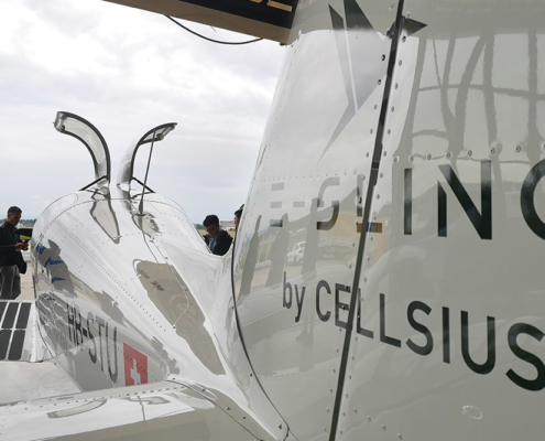 Kleines Sportflugzeug für zwei Personen, vom Heck her aufgenommen. Auf dem Flugzeug sind diverse Sponsoren aufgeführt, und die Flugzeug-Kennzeichnung ist HB-STU.