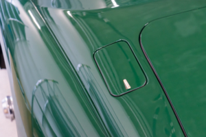 Hinter dem ehemaligen Tankdeckel befindet sich die Ladedose des elektrifizierten Jaguar XK150. Statt eines Schlosses ist nun ein chromefarbiger kleiner Halter angebracht, an dem die Klappe angehoben werden kann