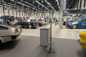 sicht vom Messestand aus in die Messehalle. Viele Fahrzeuge, vor allem Porsche