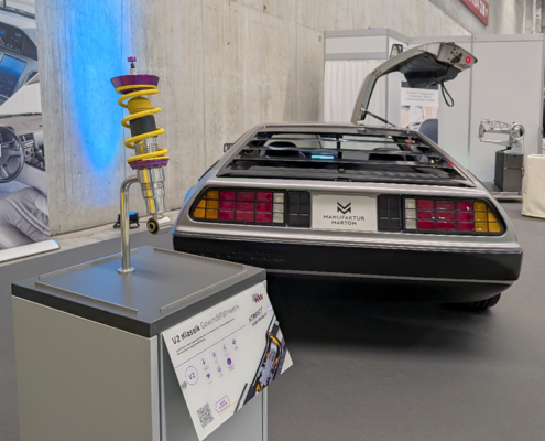 manufakturmarton_SCW2026_20260531_065935236 Fahrwerk mit DeLorean im Hintergrund. Die Feder des Fahrwerks ist gelb.