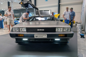Der DeLorean von vorne. Es stehen Leute um das Fahrzeug und betrachten es.